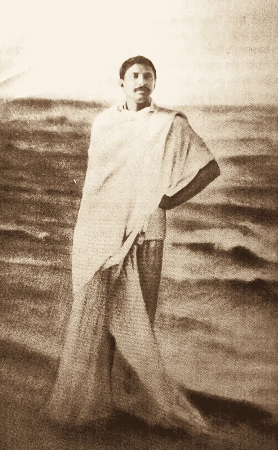 Thakur Anukulchandra standing in the sea at Puri, wrapped in a white shawl