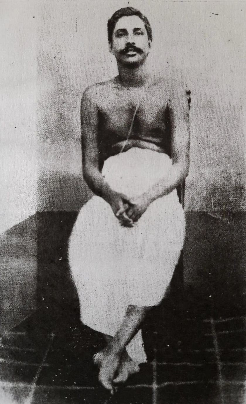 Thakur Anukulchandra seated on the floor in white, hands clasped