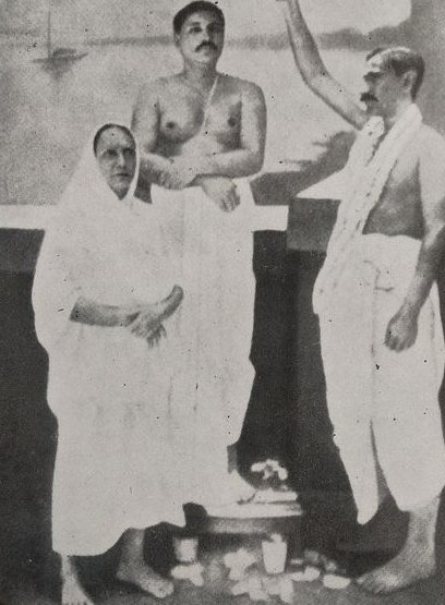 Manomohini Devi in a white sari standing beside her son, Thakur Anukulchandra; Ananta Maharaj stands beside them